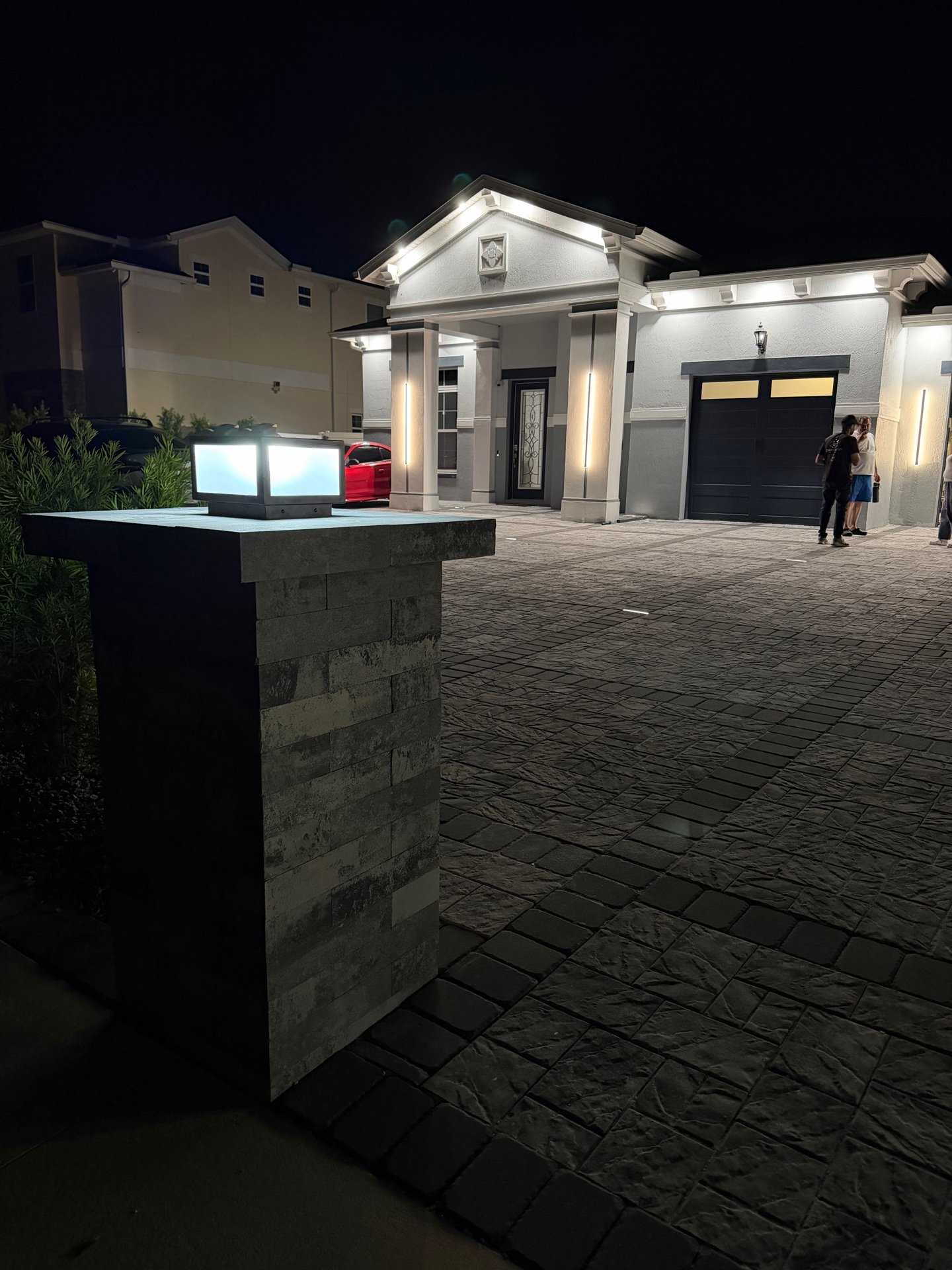 Pillar lantern lit at night with house in background