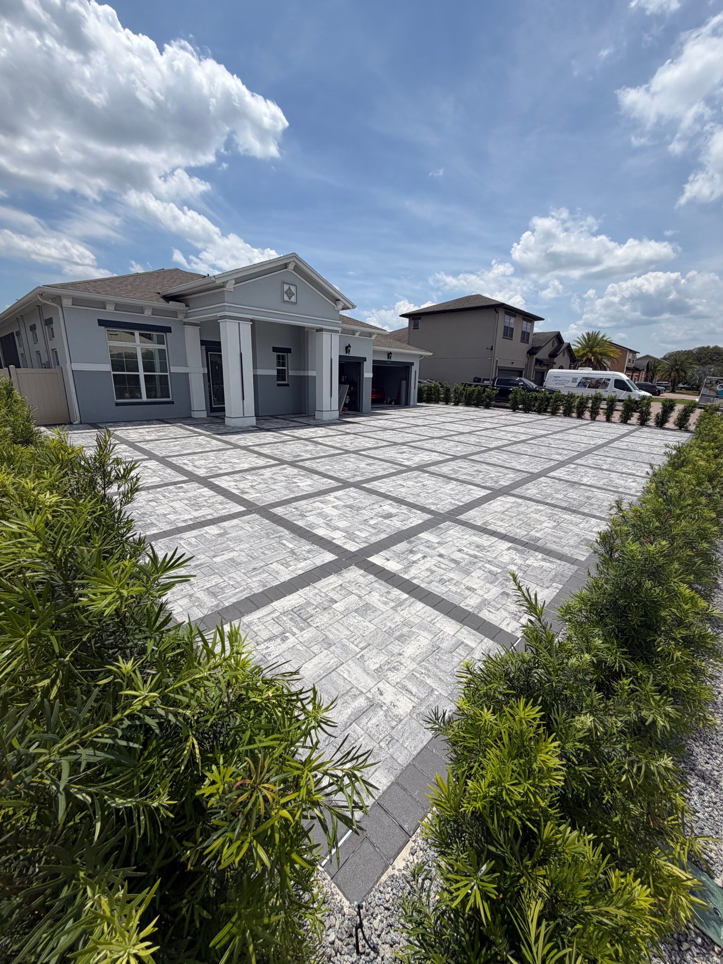 Wide front view of grey paver driveway during the day