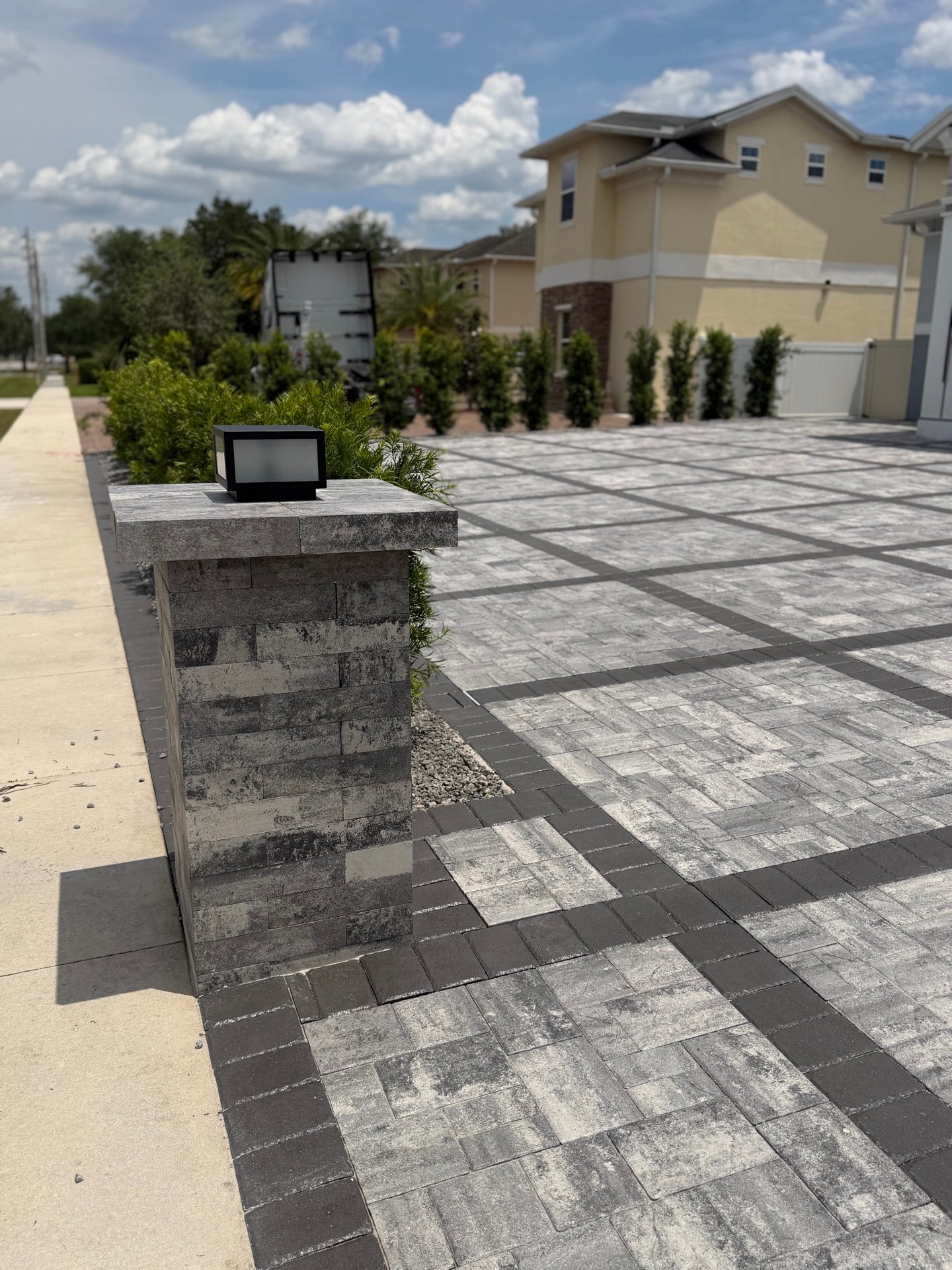 Stone pillar with lantern next to paver driveway