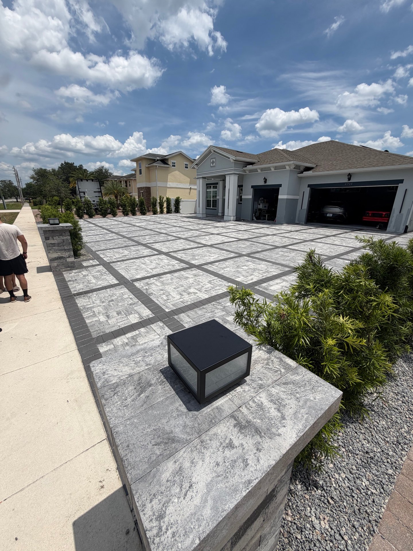 Modern paver driveway with stone pillar at daytime
