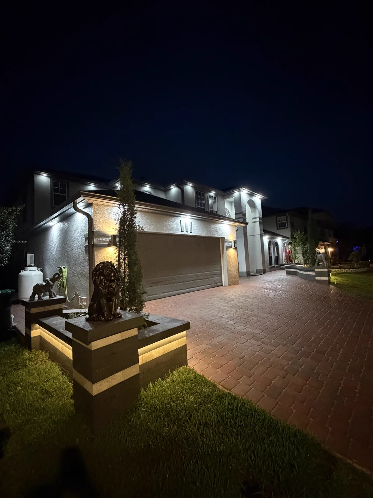 Luxury paver driveway with landscape lighting at night